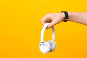 Close up photo of male hand holding white wireless headphones