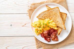Scrambled egg with bread toasted and bacon for breakfast photo