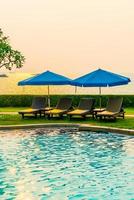 Beach chairs or pool beds with umbrellas around swimming pool at sunset time photo