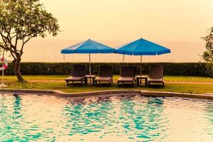 Beach chairs or pool beds with umbrellas around swimming pool at sunset time
