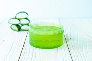 Aloe vera gel with aloe sliced on wood background photo