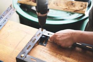 hágalo usted mismo, los artesanos utilizan taladros eléctricos para ensamblar piezas de hierro viejas. haz un estante en tu fin de semana libre foto