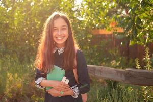 pretty young girl with a backpack and notepad. Schoolgirl teenager girl smiling with notepad. photo