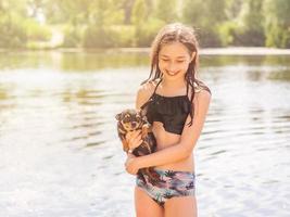 una niña con un perro pequeño en un día soleado de verano. feliz adolescente con perro chihuahua. río, verano foto