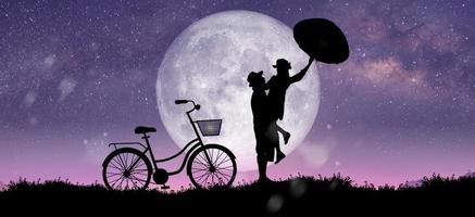 Silhouette at night landscape of couple or lover dancing and singing over the full moon photo