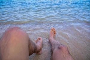 el hombre está en la playa y los pies en el mar foto