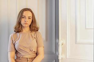 una linda chica joven y elegante está sentada en la puerta de su habitación. adolescente. tristeza foto