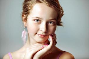 Close-up portrait of a young girl with festive makeup for a party. Valentine's Day. Earrings-feathers in the ears of the model