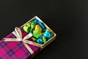 Colored gift box with satin bow with origami paper stars on black background. Gifts for the holidays. photo