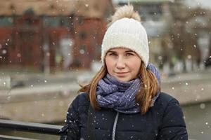 retrato de una hermosa joven sonriente feliz en el fondo de la ciudad. moda de invierno, concepto de vacaciones de navidad. foto