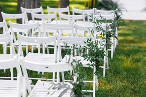 decorated white chairs at a wedding ceremony photo