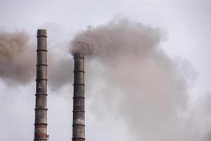 Smoke from two industrial chimneys, pipes, against the sky. Global warming. Air pollution. Ecological pollution. Air emissions polluting the city. Industrial waste is hazardous to health. photo