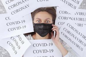 shocked young woman in medical mask with coronavirus, covid-19 isolated on quarantine at home and talking on the cellphone for help. selective focus. photo