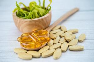 Vitamin C pills and vitamin E omega 3 fish oil on wooden spoon for good health. photo