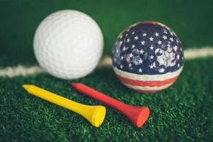 Golf ball with USA flag and tee on green lawn or grass, most popular sport in the world. photo