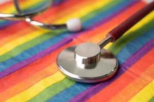 Red stethoscope on rainbow flag background, symbol of LGBT pride month celebrate annual in June social, symbol of gay, lesbian, bisexual, transgender, human rights and peace. photo