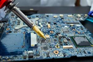 E-waste, technician repairing inside of hard disk by soldering iron. Integrated Circuit. the concept of data, hardware, technician and technology. photo