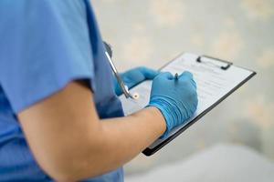 médico asiático con protector facial y traje de ppe nuevo normal para comprobar que el paciente protege la seguridad infección brote de coronavirus covid-19 en la sala de cuarentena del hospital de enfermería. foto