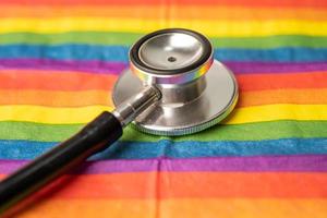 Black stethoscope on rainbow flag background, symbol of LGBT pride month celebrate annual in June social, symbol of gay, lesbian, bisexual, transgender, human rights and peace. photo