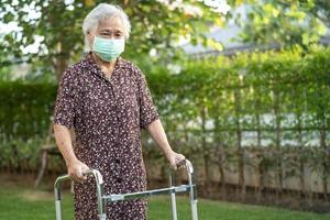 Asian senior or elderly old lady woman patient walk with walker in park,  healthy strong medical concept.