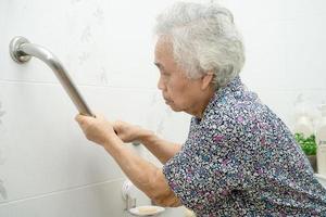 Asian senior or elderly old lady woman patient use toilet bathroom handle security in nursing hospital ward, healthy strong medical concept. photo