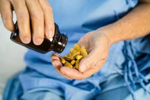 Asian doctor holding and pour and hold vitamin c pills medicine from the bottle to patient for treatment infection in hospital, Pharmacy drugstore concept. photo