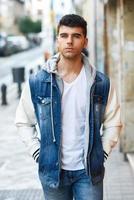 Handsome young man with blue eyes posing near a wall photo