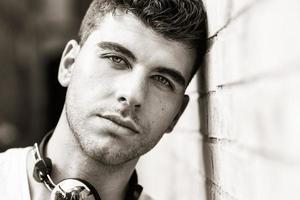 Young man in urban background listening to music with headphones photo