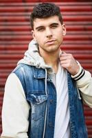 Handsome young man with blue eyes posing near a wall photo