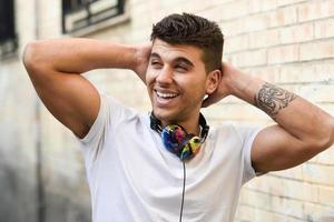 Young man in urban background listening to music with headphones photo