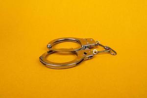 handcuffs on yellow background, concept of arrest