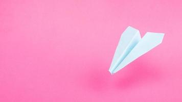 blue origami plane on pink background, travel flights copy space photo