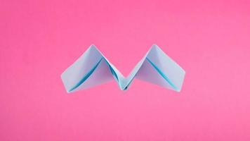 paper blue airplane on pink background back view, fly away photo