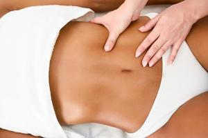 mujer recibiendo masaje de abdomen en el centro de bienestar spa.