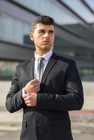 Young businessman near an office building wearing black suit photo