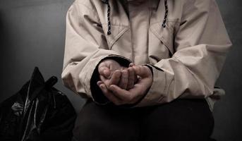 a beggar with outstretched hands asks for money sits on the floor. photo