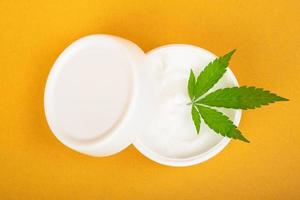 cosmetic cream for combating wrinkles on the skin with cannabis on a yellow background photo