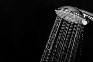 Scattering splashing water  by a shower head on a dark background photo