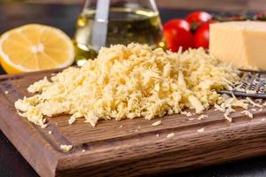 Fresh hard cheese grated on a large grater on a wooden cutting board photo