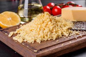 Fresh hard cheese grated on a large grater on a wooden cutting board photo