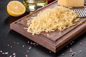 Fresh hard cheese grated on a large grater on a wooden cutting board photo