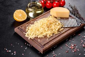 Fresh hard cheese grated on a large grater on a wooden cutting board photo