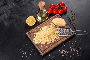 Fresh hard cheese grated on a large grater on a wooden cutting board photo
