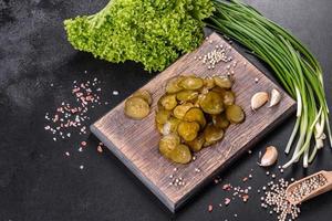 Tasty salty spicy pickled cucumber cut with rings on a wooden cutting board photo