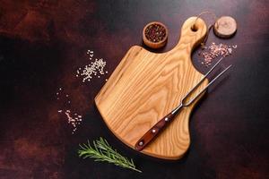 Cutting board with salt, spices and herbs on a dark concrete background photo