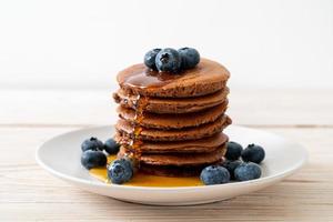Chocolate pancake stack with blueberry and honey on a plate photo