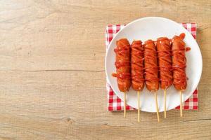 Brocheta de salchicha frita con salsa de tomate en una placa blanca. foto