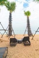 Empty beach chair with palm trees on beach with sea background photo