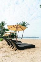 Empty beach chair with palm trees on beach with sea background photo