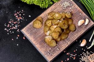 Sabroso pepino encurtido picante salado cortado con anillos sobre una tabla de cortar de madera foto